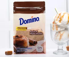 Bolsa marrón con azúcar Domino y helado junto a ella.
